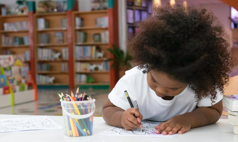 Little African girl enjoy drawing in kids room.